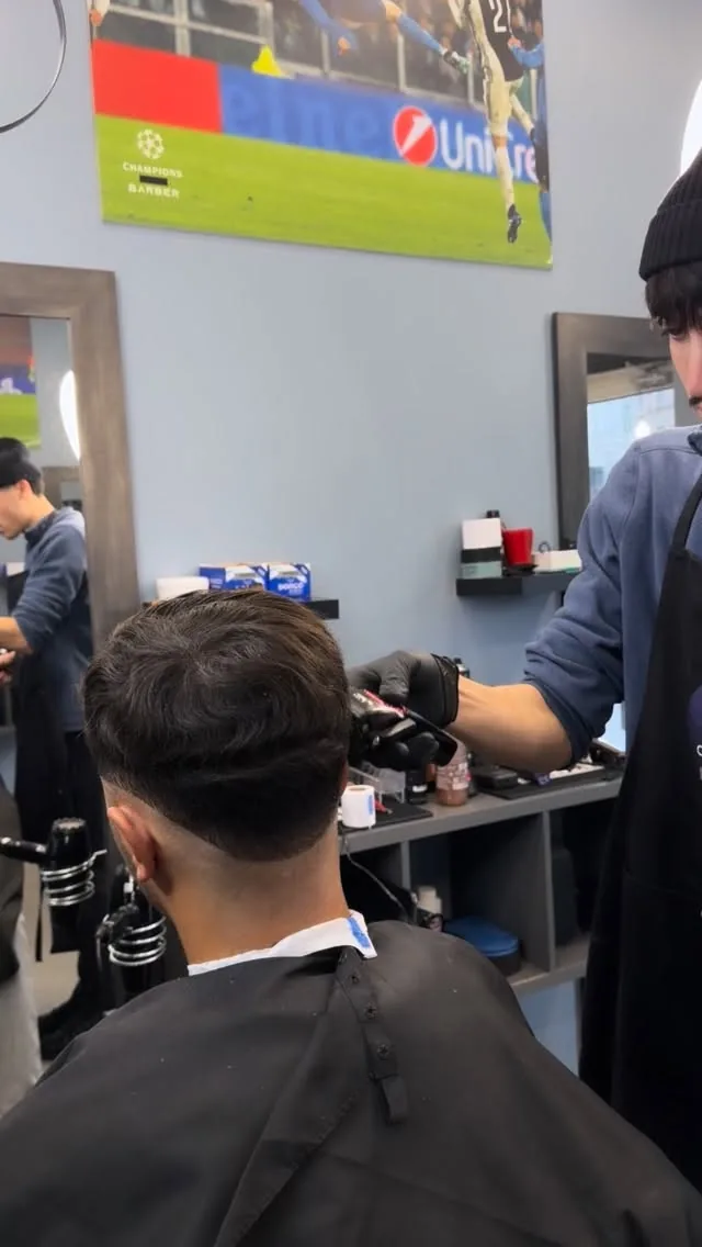 Un barbier de Champions Barber termine une coupe sous l'affiche du salon