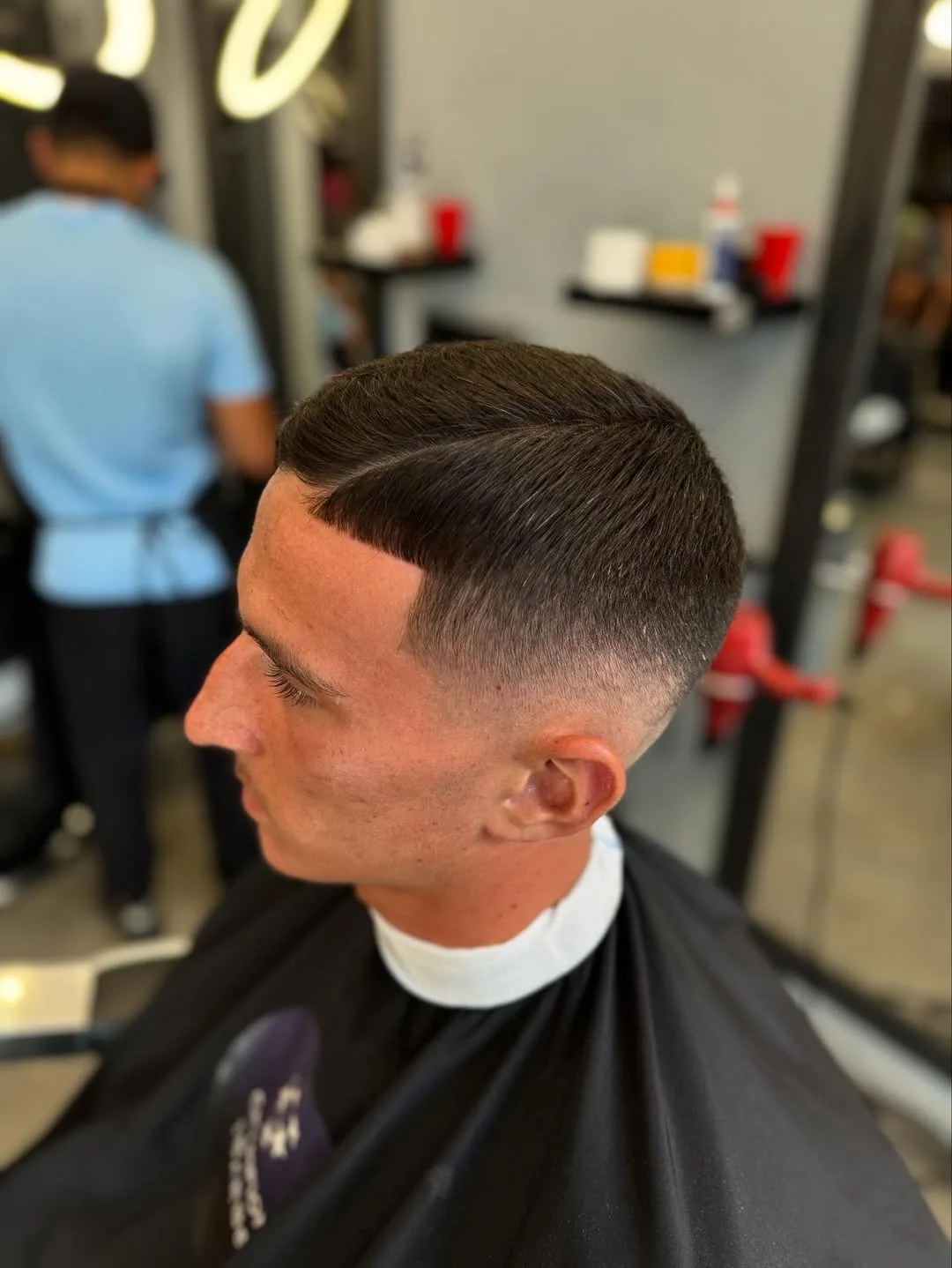 Dégradé net et raie tracée, vu de profil dans le salon Champions Barber